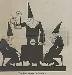 Three black-robed men with pointy hoods around a table that has a skull lying on top. One man is holding a sign saying "Death to the pacifists". Text underneath reads "The Inquisition in America".