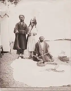 Persian dervish, holding a huge snake in his arms (1870s)