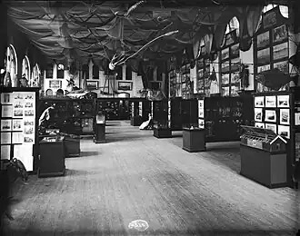 #42 (24/9/1877), Fisheries Court exhibit at the United States National Museum in Washington, D.C. (in what is now the Arts and Industries Building), as it appeared in 1886. J. H. Emerton's giant squid and giant octopus models are suspended from the ceiling surrounded by fishing nets (see also engraving of same).