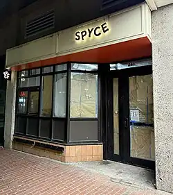 A closed-up restaurant with a sign that reads "Spyce", and with the windows blocked off inside with brown paper