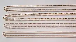 4 golden chains are on display in this photograph, each one has a different style, on some all the links look the same, on others there are longer links between a section of short links.