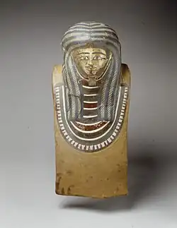 Gilded and painted mask with painted decoration including a striped wig and wide necklace