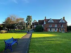 A photo of the former hunting lodge at Garth Park in the sunshine with a green lawn in the foreground.