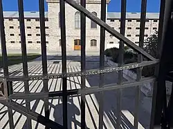 Photo of iron gates with an old brick building in the background.