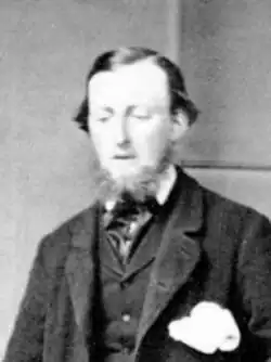 A cropped black and white photo showing George Hunter Cary looking down and to his right, with his mouth slightly open. He is wearing a suit, and has a chin-strap beard. He has dark hair.