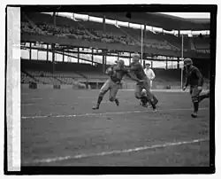Grayscale photograph of four football players and a referee at an arena