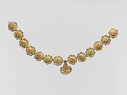 Mycenaean necklace; 1400–1050 BC; gilded terracotta; diameter of the rosettes: 2.7 centimetres (1.1 in), with variations of circa 0.1 centimetres (0.039 in), length of the pendant 3.7 centimetres (1.5 in); Metropolitan Museum of Art (New York City)