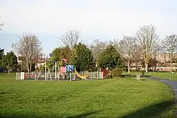 small park with tower blocks along the horizon. A bright children's playground dominates