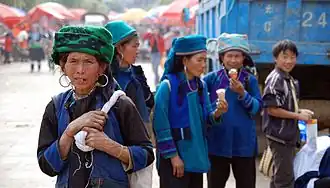 Hani ladies eating ice cream in Laomeng village during market day