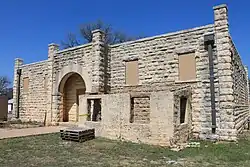 Two-story tan stone building with windows covered