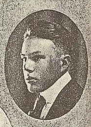 A black-and-white photograph. Enclosed in an oval, the face of a young man in a suit and tie faces leftward.