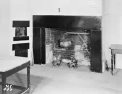 A black-and-white image of the kitchen fireplace, which has a mantelpiece
