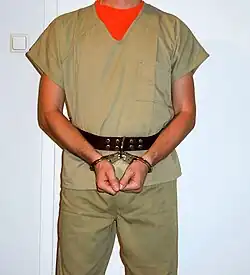 Inmate in hinged handcuffs attached to a leather belt