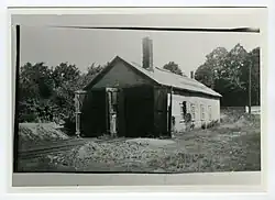 A single story building with two large doors. Train tracks lead into both doors.