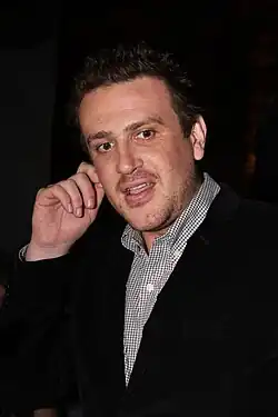 a man tugging his ear stares to someone off-camera