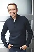 Jeff Koons standing and smiling.