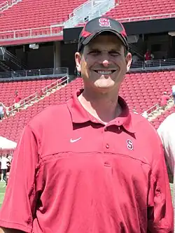 A color photograph of a man wearing a red hat and a red polo shirt