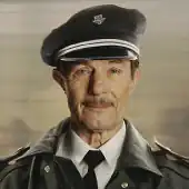 A portrait photograph of a smiling man wearing a peaked cap.