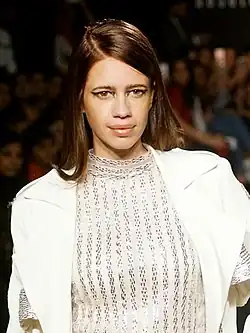 Koechlin posing for the camera in a white coat and a sheer dress