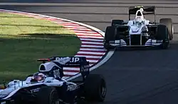 A white single-seater racing car is driven around a tarmac course.