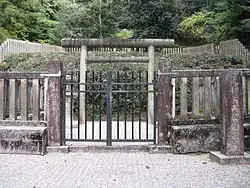 Stone lanterns and torii behind stone fence.