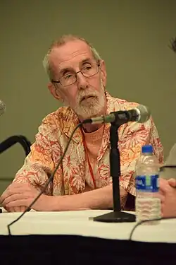 Giffen seated at a panel, wearing a Hawaiian shirt