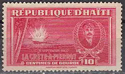 a red postage stamp bearing the words République d'Haïti, with a picture of a ship exploding, as seen from the shore, and an inset image on the right depicting Killick, underneath the images it reads "6 Septembre 1902, La Crête-à-Pierrot, Centimes De Gourde 10