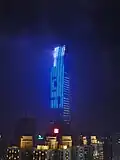 The KK100 building at night, with the top visible through low clouds.
