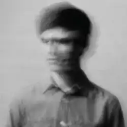 A blurred black and white picture of a man moving his head from left to right.