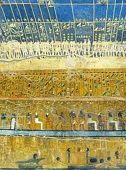 Walls of an ancient tomb, covered in paintings, showing golden stars on a blue background, rows of hieroglyphs beneath.