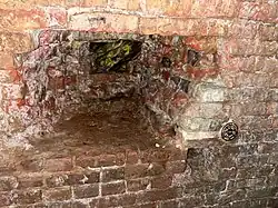 This large hole gives an idea how thick the brick lining is. Note survey marker.