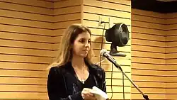 Leila Cobo speaking in front of a microphone