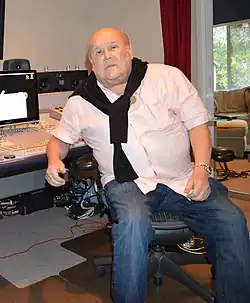A man wearing a black scarf is sitting in a recording studio.