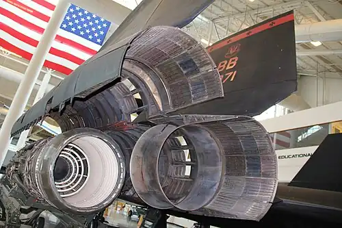 Ejector nozzle at the rear of the powerplant. The engine nozzle (left) is the first component in the exhaust system, followed by the secondary and tertiary air flows and ejector nozzle. The tertiary doors are open. There is a fixed convergent/divergent shroud and the ejector nozzle trailing flaps are at their minimum area (closed). These nozzle and door positions correspond with full afterburner up to transonic speed, after which the doors close and flaps start to open. Secondary air from the inlet passes between the engine and nacelle and joins the blow-in door air to control the expansion of the engine exhaust through the shroud and trailing flaps.