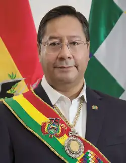 Luis Arce in the Casa Grande del Pueblo, invested with the symbols of command. Behind are the dual flags of Bolivia: the national flag and the Wiphala.
