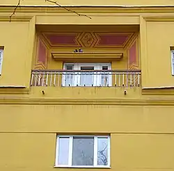 Portion of yellow apartment house with small balcony