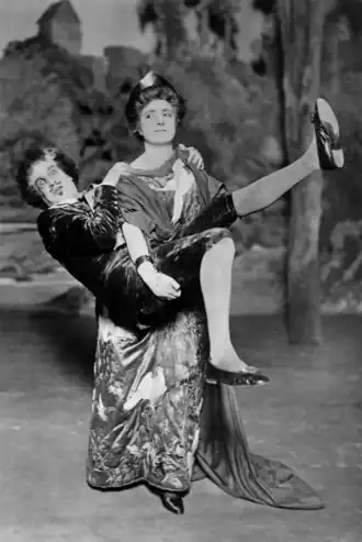 White woman in Victorian "aesthetic" costume carrying off a white man, who looks comically terrified