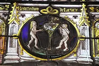 Medieval stained glass medallion depicting the Temptation of Adam and Eve, a man and a woman are naked around a tree bearing fruit and in which there is a snake, the woman is holding an apple and the man has begun to eat another.