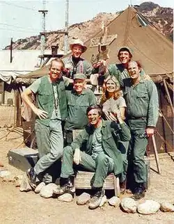 The cast from season 8 onward (clockwise from left): Mike Farrell, William Christopher, Jamie Farr, David Ogden Stiers, Loretta Swit, Alan Alda, and Harry Morgan