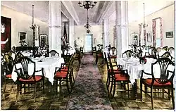 Large room with pillars and chandeliers with tables and wide chairs