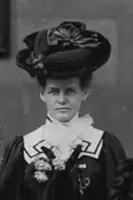 B&W portrait photo of a woman wearing a dark hat and dark dress