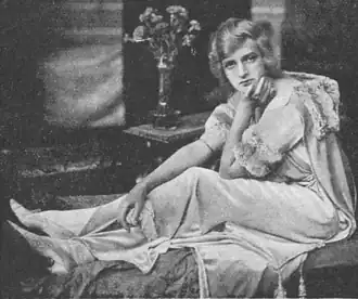 Young white woman, seated, wearing negligée and looking fractious