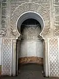 Mihrab of the prayer hall with carved stucco decoration, including darj wa ktaf motifs and an Arabic inscription in kufic script