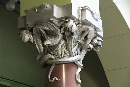 Sculpted column capital with snakes and reptiles at the top of the stairway