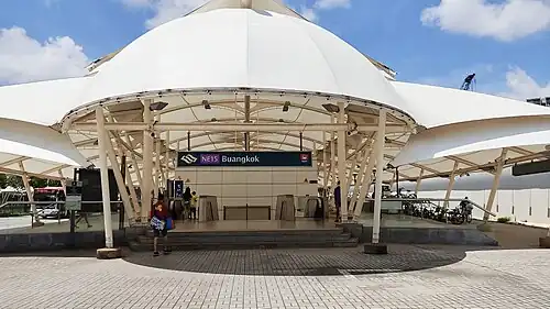 The entrance of Buangkok station is characterized by a distinctive, large, white Teflon sheet as its canopy. A series of steps lead up to the entrance.
