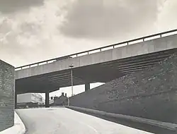 View of a ramp leading up to the Moat Street roundabout car park with brick walls on both sides, the ring road flyover passing from right to left over the car park