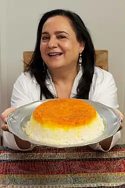 A woman holding a plate of golden crusted rice