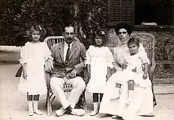 Black and white photograph showing a couple sitting with three girls dressed in white.