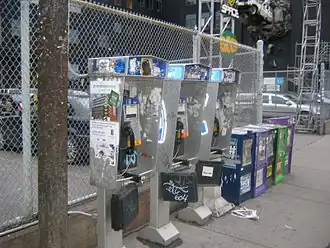 Nortel Millennium payphones operated by Bell Canada covered with graffiti and notices in Toronto. Telephone directory are contained in weatherproof holders hanging from the bottom of each phone.