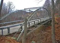 Bridge seen from side with some tree trunks in front, and side structure visible